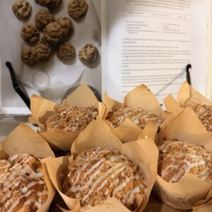 Apple walnut crumb muffins in parchment wrappers with icing drizzle