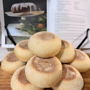 Fresh English muffins stacked on a wooden board