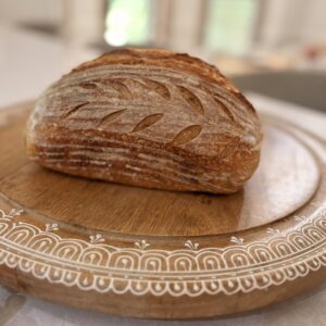 Classic sourdough loaf with leaf scoring on a wooden board